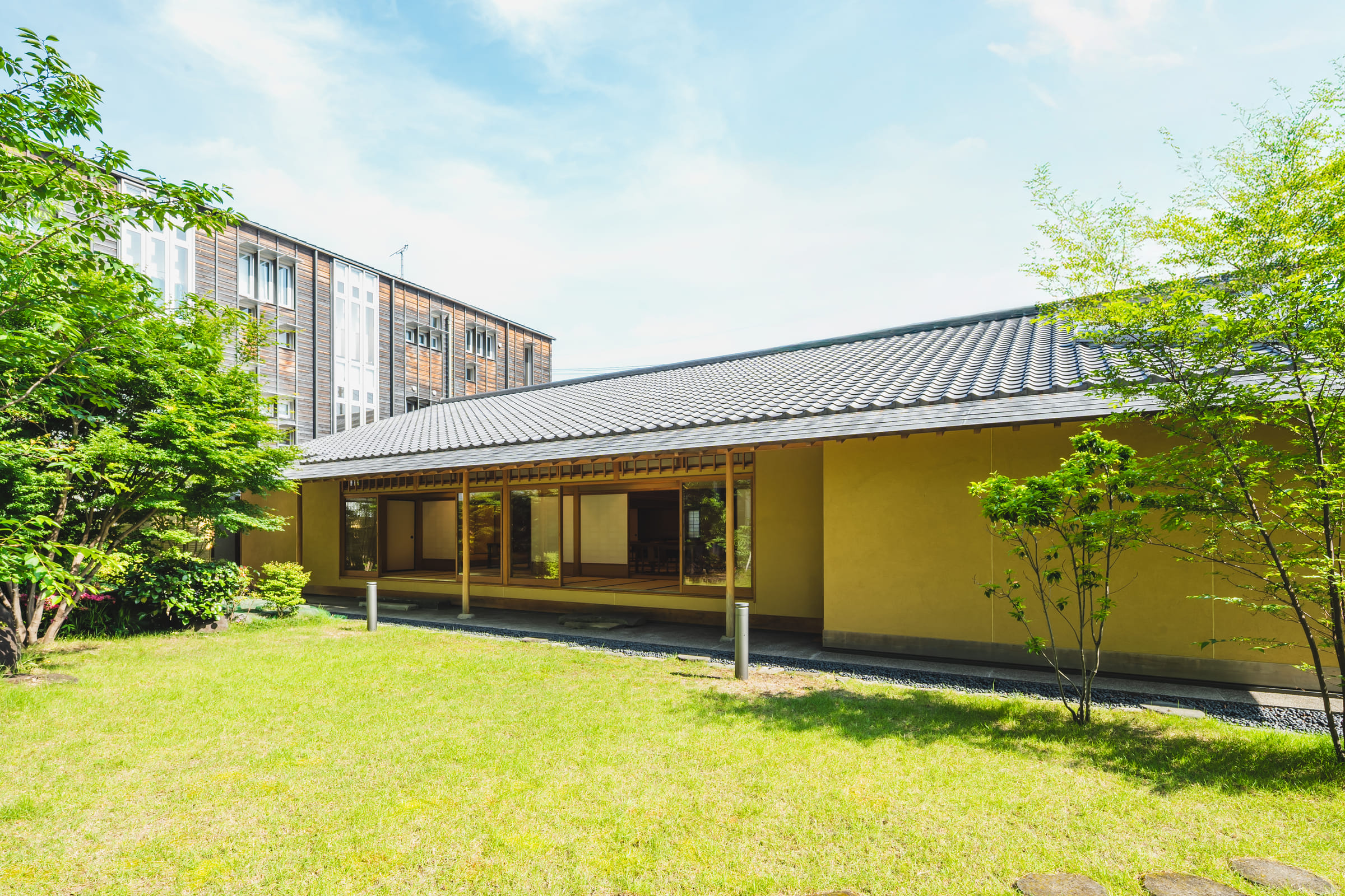 芝生の庭に面した和風建築の外観。深い軒と瓦屋根
